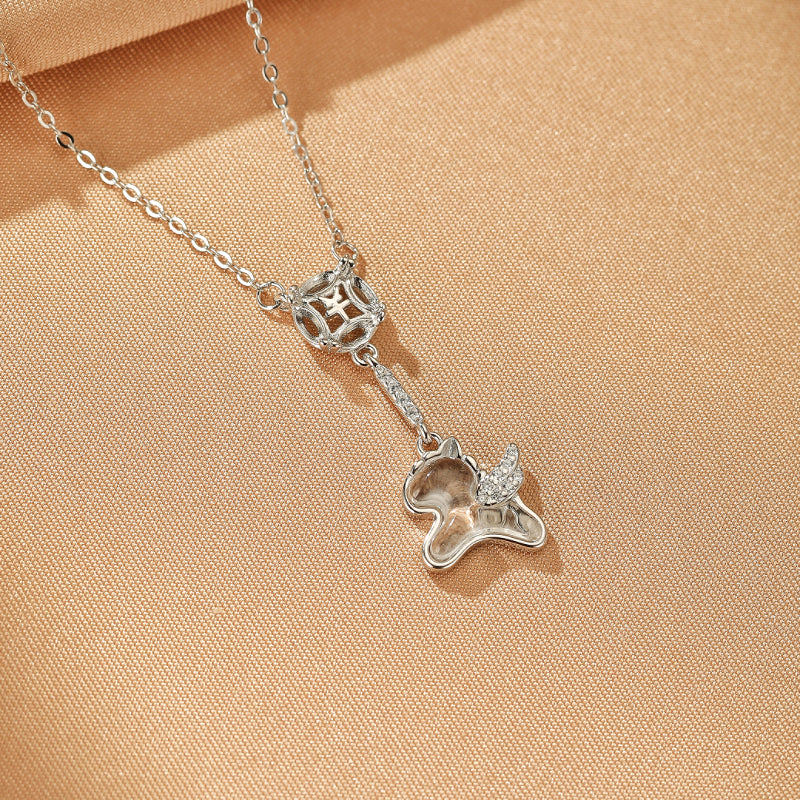 Collier "Fortune Ailée" en argent avec un pendentif en cristal de roche en forme de licorne ailée scintillante et une petite sphère ajourée ornée de symboles.