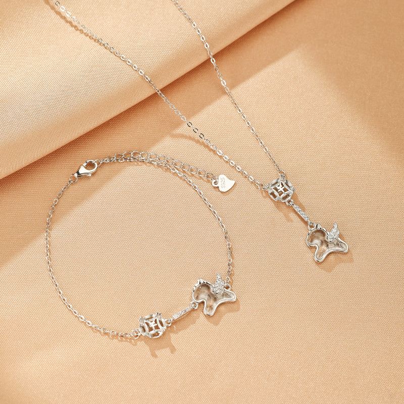 Ensemble de bijoux en argent sterling, comprenant un collier et un bracelet ornés d'un pendentif en forme d'éléphant stylisé avec des ailes et incrusté de cristaux.