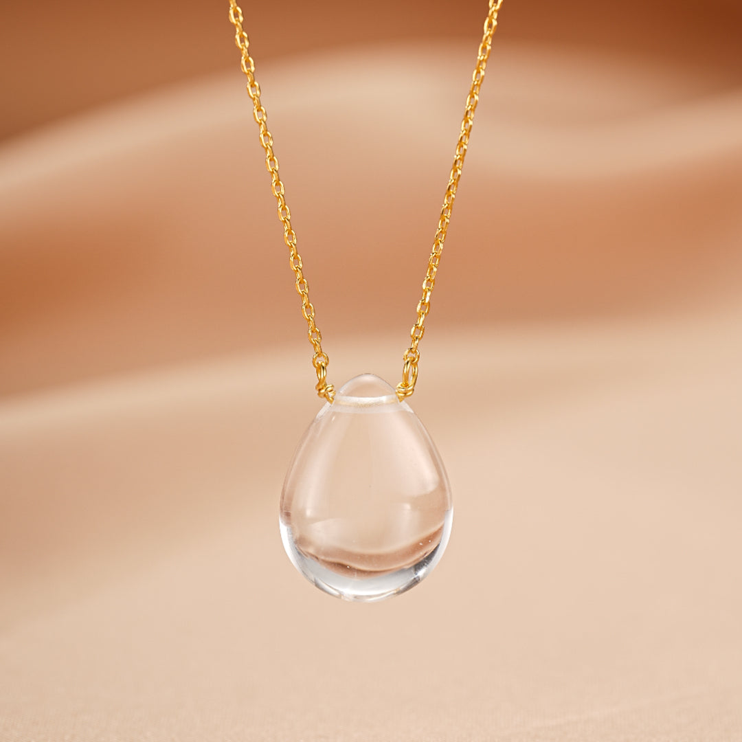 Collier pendentif en forme de larme en cristal de roche, monté sur une fine chaîne en argent plaqué or.