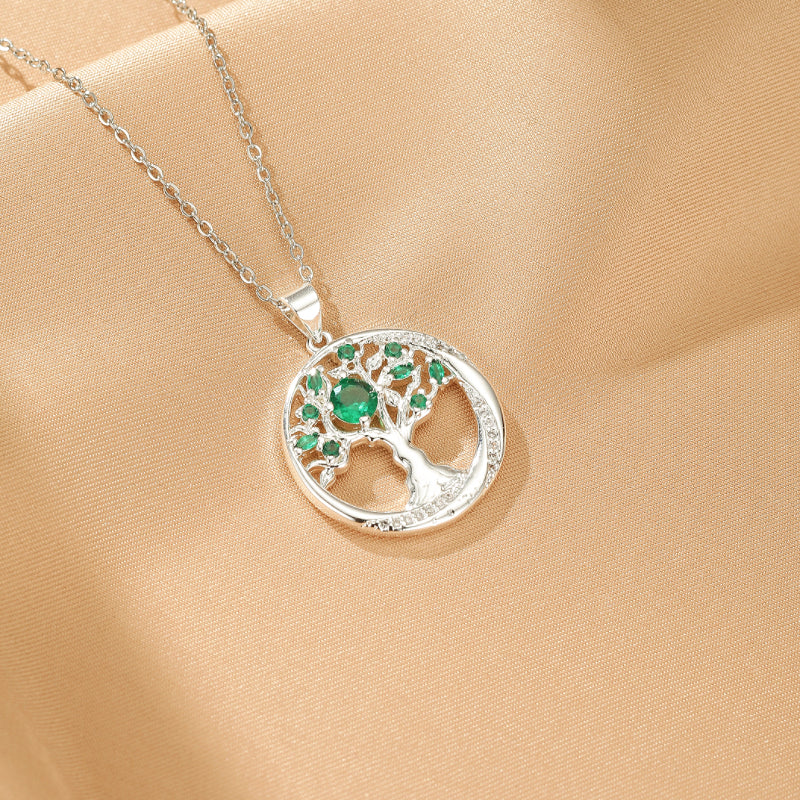 Collier Arbre Éternel en argent avec un médaillon rond orné d'émeraudes et de détails scintillants.