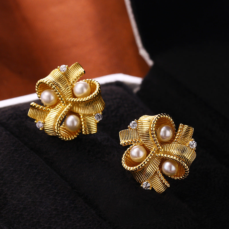 Paire de boucles d'oreilles en forme de nœud torsadé en plaqué or 18 carats, serties de petites perles et de cristaux brillants.