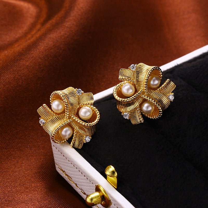 Paire de boucles d'oreilles en forme de nœud en plaqué or 18K, ornées de perles et de petits cristaux, présentées dans une boîte bijou.