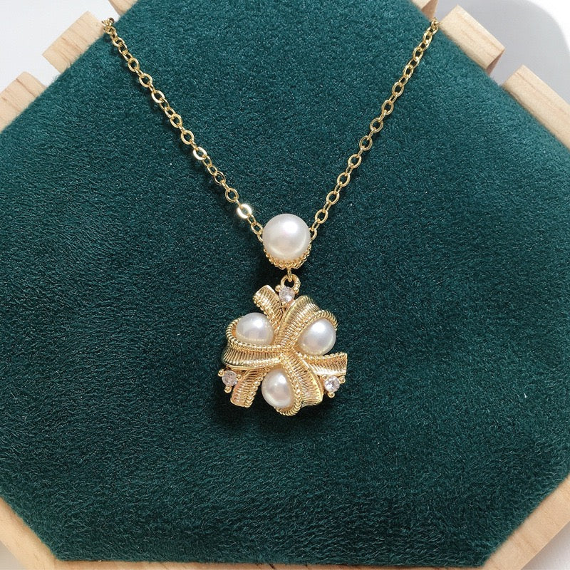 Collier en plaqué or 18K avec pendentif nœud orné de perles et de zircons, et une perle suspendue à la chaîne.