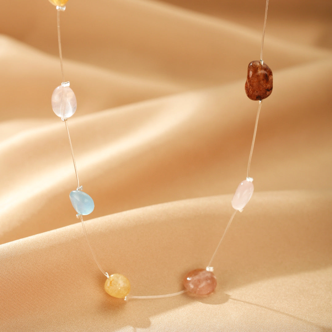 Collier flottant délicat orné de pierres naturelles multicolores sur un fil transparent, modèle Mosaïque Lumineuse sur fond satiné beige