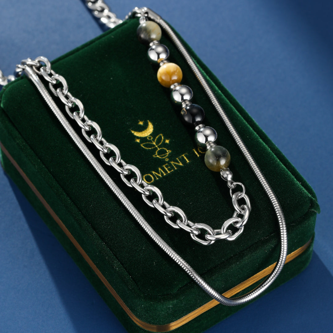 Collier homme "Fusion Urbaine" avec perles œil de tigre, perles noires et détails argentés, présenté sur un écrin en velours vert.