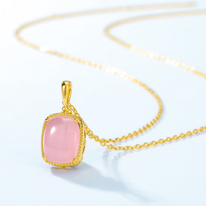 Un collier en argent plaqué or avec un pendentif carré en quartz rose délicat, sur une chaîne fine dorée.