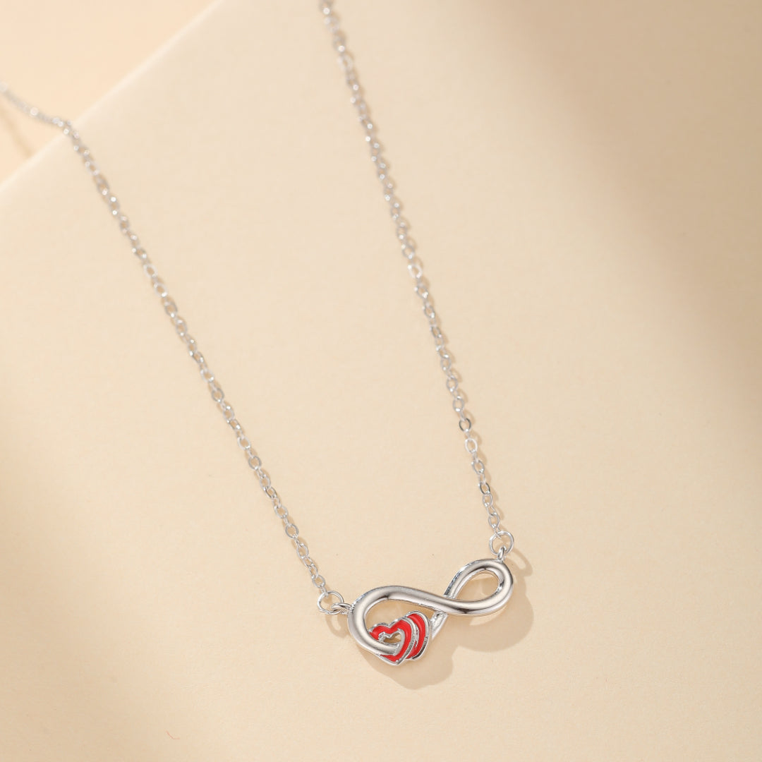 Collier en argent 925 avec un symbole de l'infini entrelacé avec deux cœurs rouges.