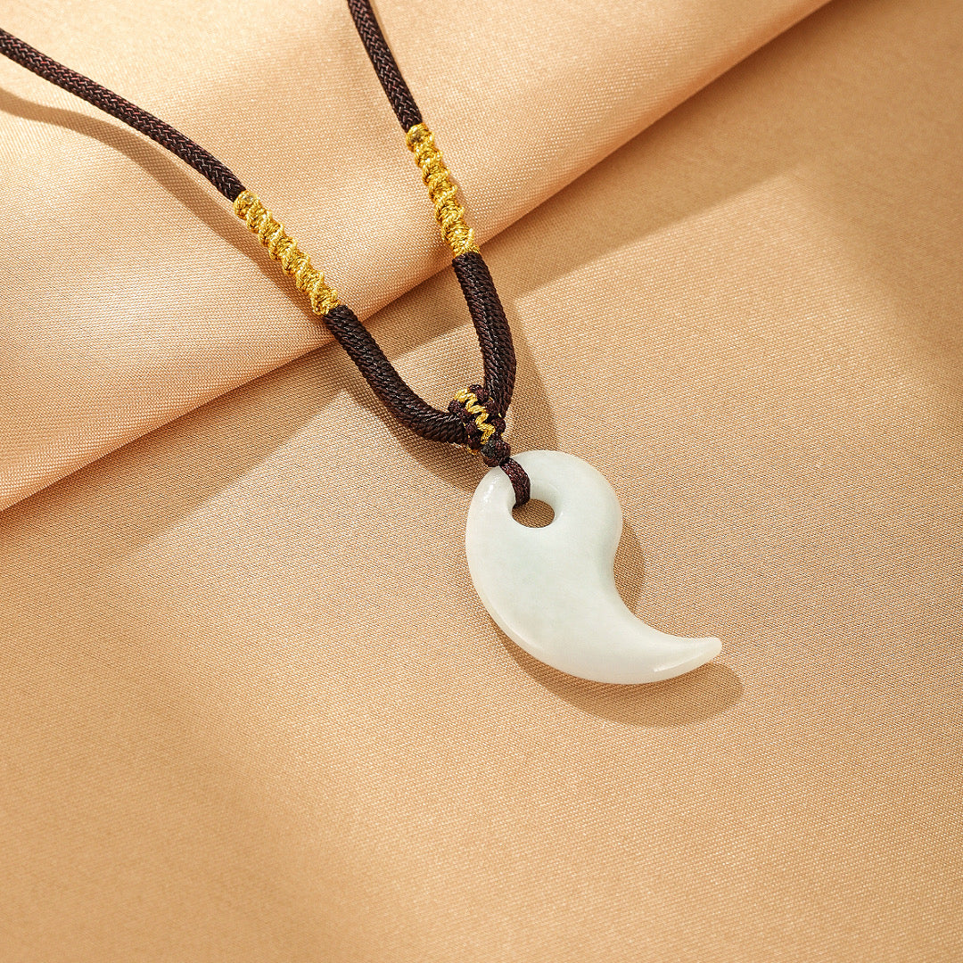 Pendentif en jade blanc en forme de croissant sur un cordon noir tressé avec des détails dorés, modèle Dualité Céleste.