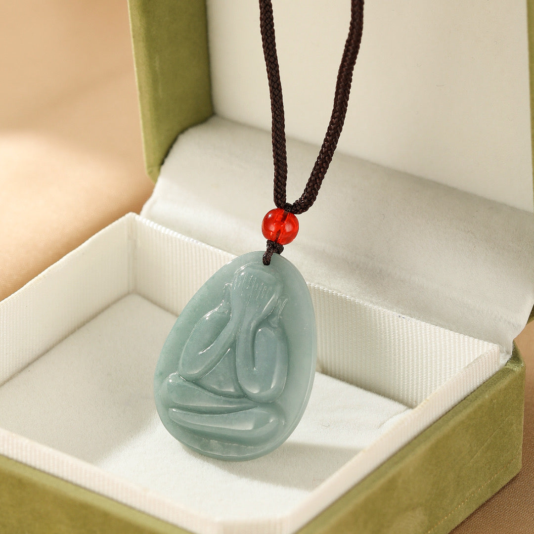 Collier pendentif en jadéite bleue sculptée Regard Intérieur, représentant une figure méditative dans son écrin de présentation.
