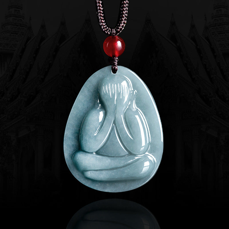 Pendentif en jadéite bleue naturelle sculpté en forme de silhouette méditative, collier artisanal Regard Intérieur monté sur cordon noir avec perle rouge.