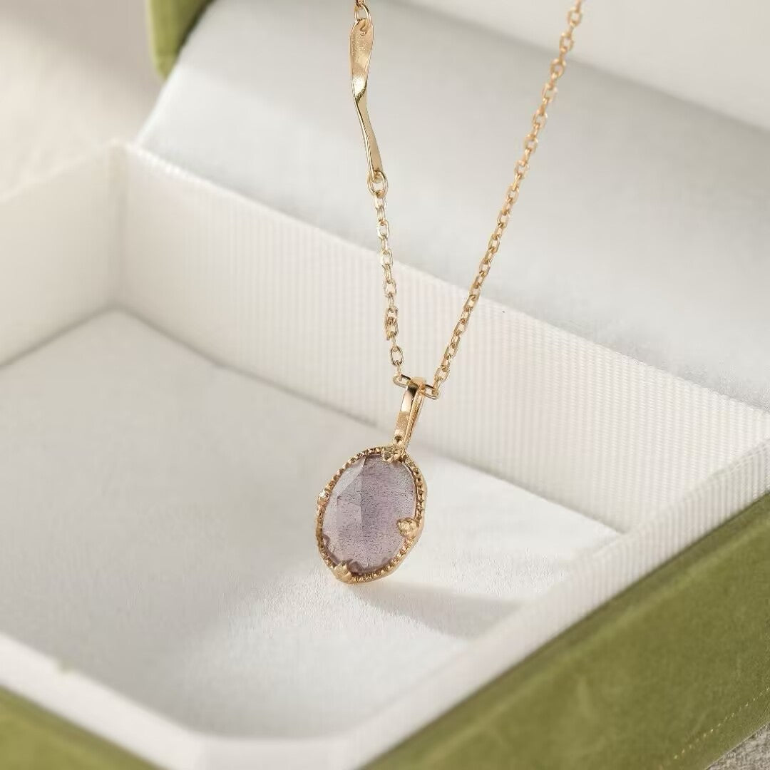 Collier fin en argent plaqué or avec un pendentif ovale en labradorite et améthyste dans une boîte cadeau verte.