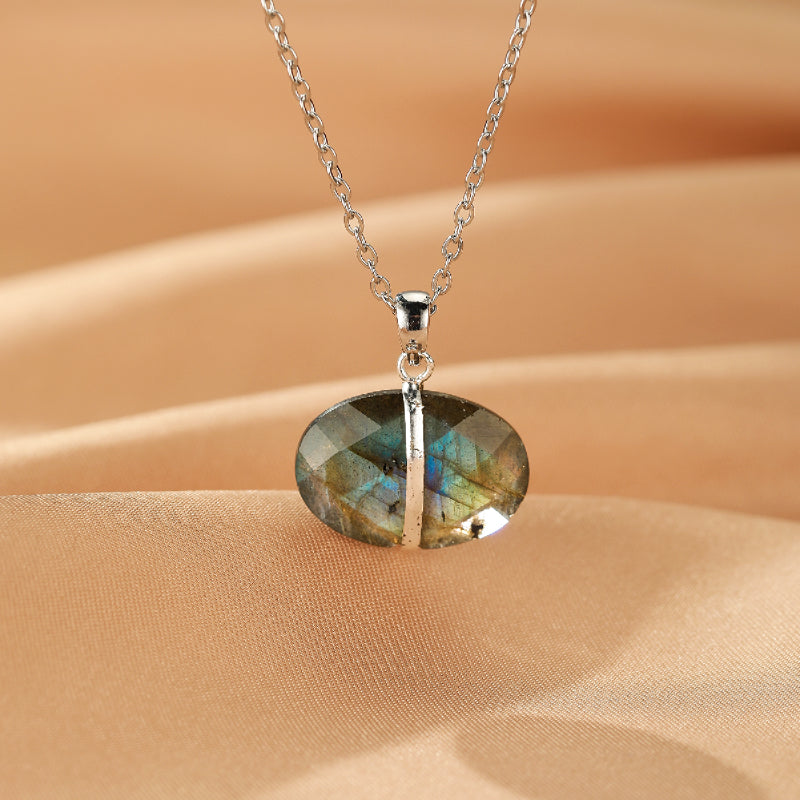 Collier avec pendentif ovale en labradorite aux reflets bleus et verts, monté sur une chaîne argentée.