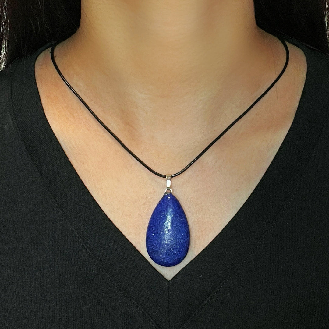 Gouttelette de collier en Lapis-Lazuli bleu profond avec un cordon noir porté par une femme.