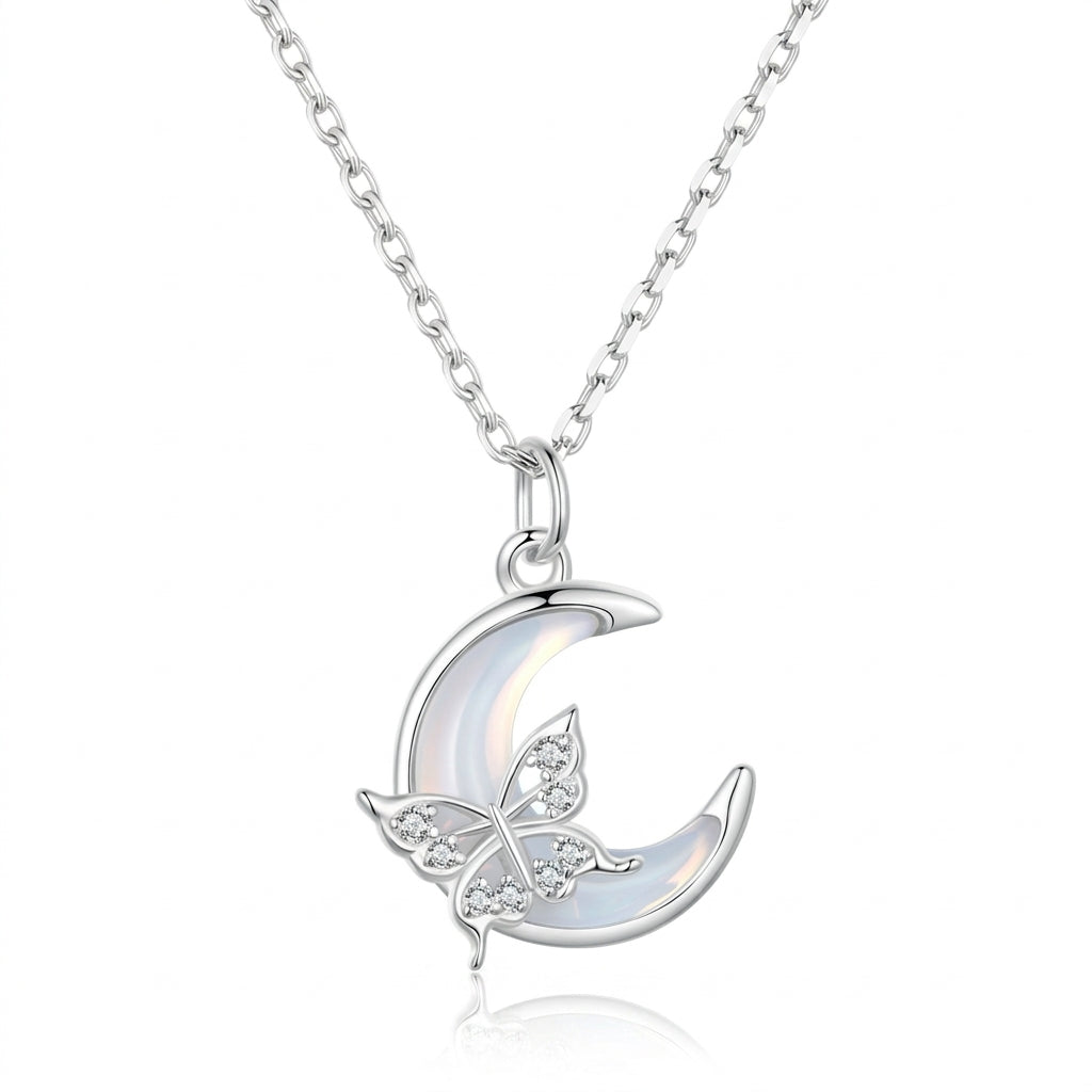 Collier en argent avec un pendentif en forme de croissant de lune orné d'un papillon incrusté de cristaux et d'une pierre nacrée.
