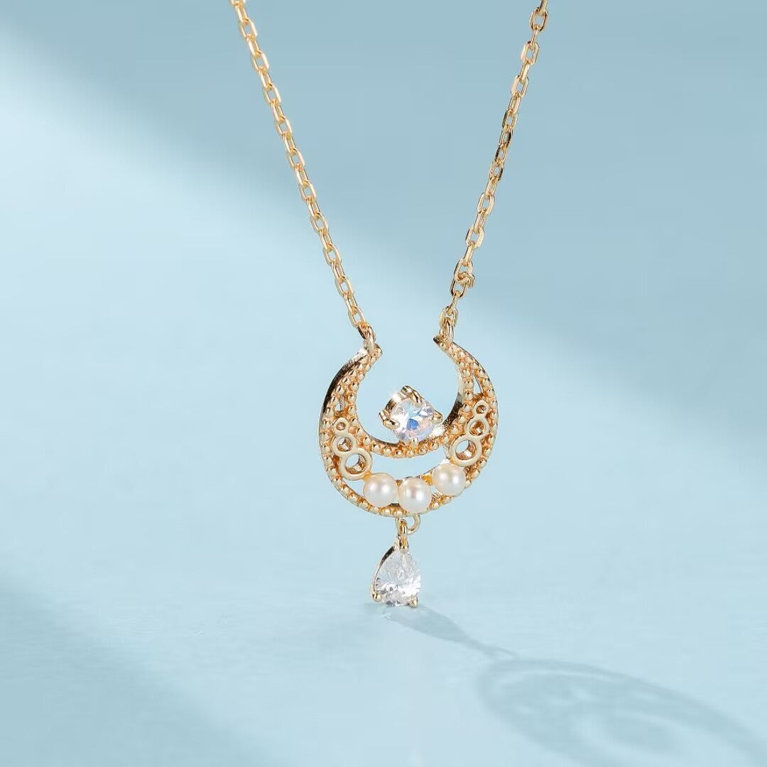 Collier en argent plaqué or orné d'une pierre de lune, de petites perles nacrées et d'un pendentif en forme de goutte d'eau, le tout monté sur un fermoir en croissant de lune stylisé.