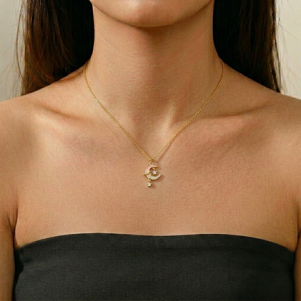 Collier plaqué or avec un pendentif en forme de croissant de lune rose orné d'une étoile scintillante et de petits zircons cubiques.