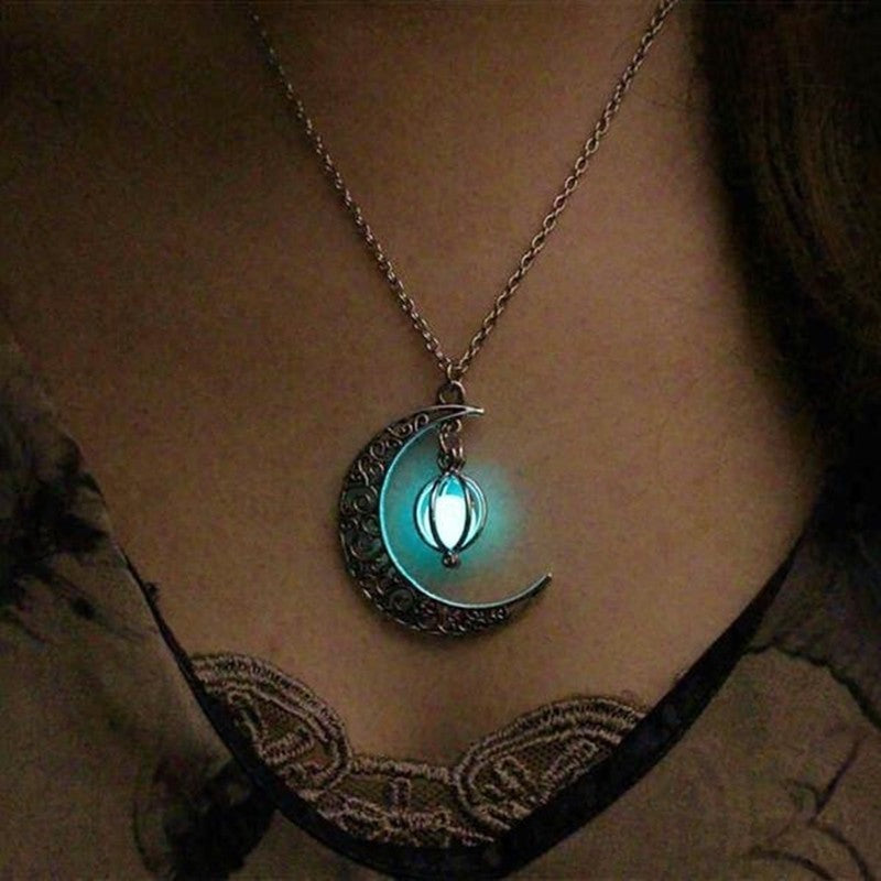 Collier en argent avec un pendentif en forme de croissant de lune orné d'une perle fluorescente bleu clair.