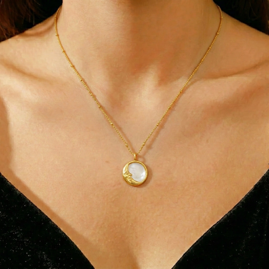 Collier en nacre avec un pendentif en forme de lune dorée, porté sur une femme.