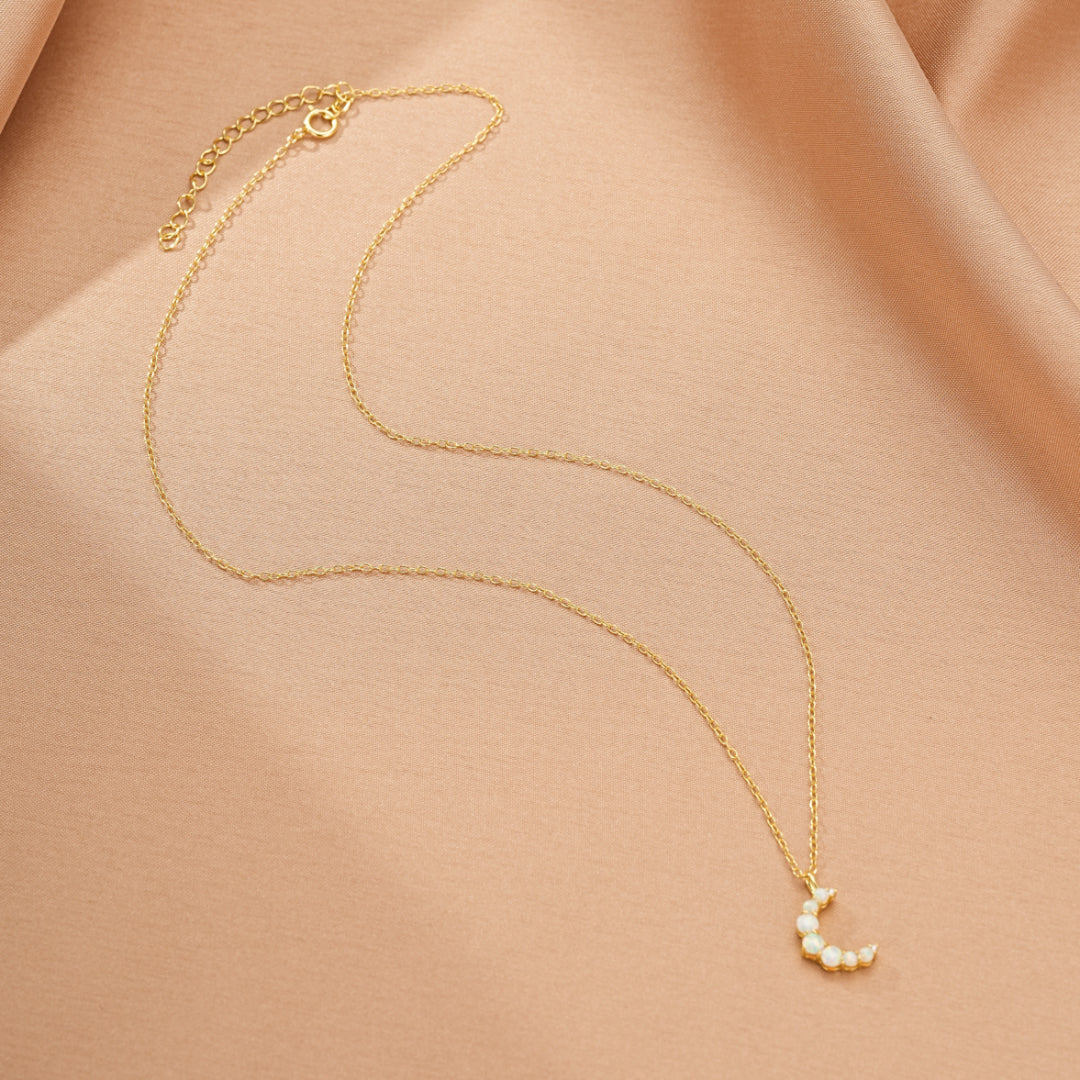 Collier en argent 925 plaqué or 18 carats avec un pendentif en forme de croissant de lune orné de petites pierres opales.