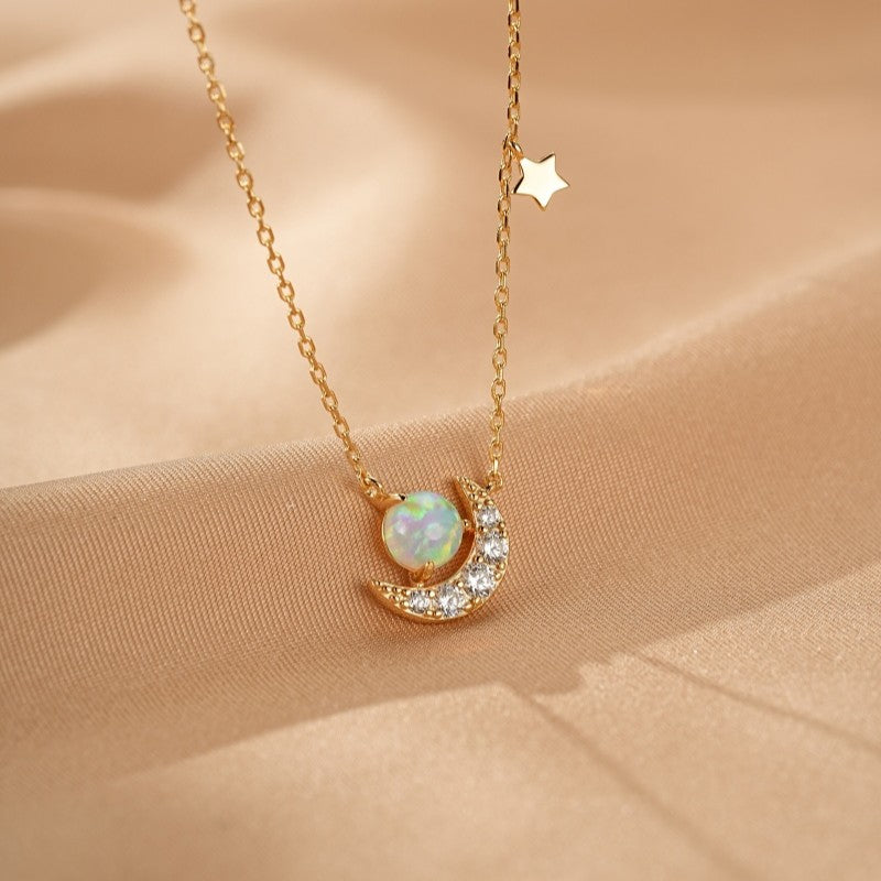 Collier en argent plaqué or avec un pendentif en forme de croissant de lune orné d'une opale blanche et de zircons cubiques, avec une petite étoile suspendue à la chaîne.