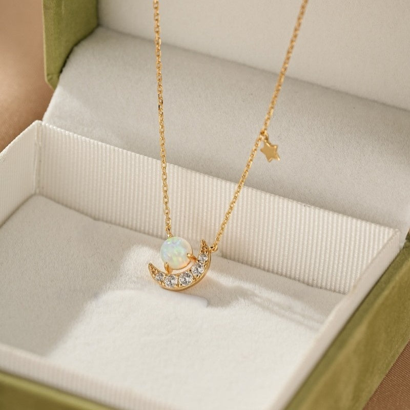 Collier en argent plaqué or avec un croissant de lune orné d'une opale et de zircons, et une petite étoile suspendue à la chaîne.