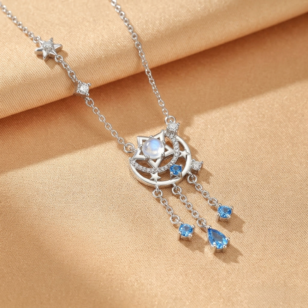 Collier en argent orné d'une pierre de lune centrale, d'une lune stylisée, d'étoiles et de pierres bleues en forme de gouttettes.
