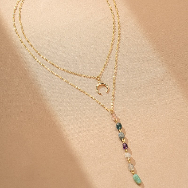 Collier double chaîne plaqué or avec un pendentif croissant de lune et une cascade de pierres naturelles colorées.