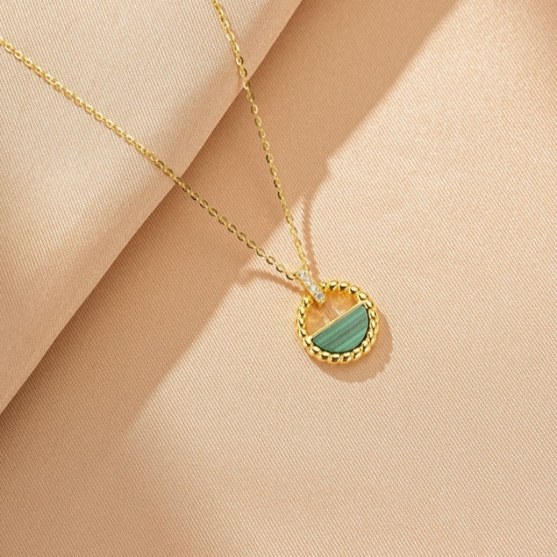 Collier en argent plaqué or avec un pendentif rond orné d'une demi-lune de malachite verte et de petits cristaux scintillants.