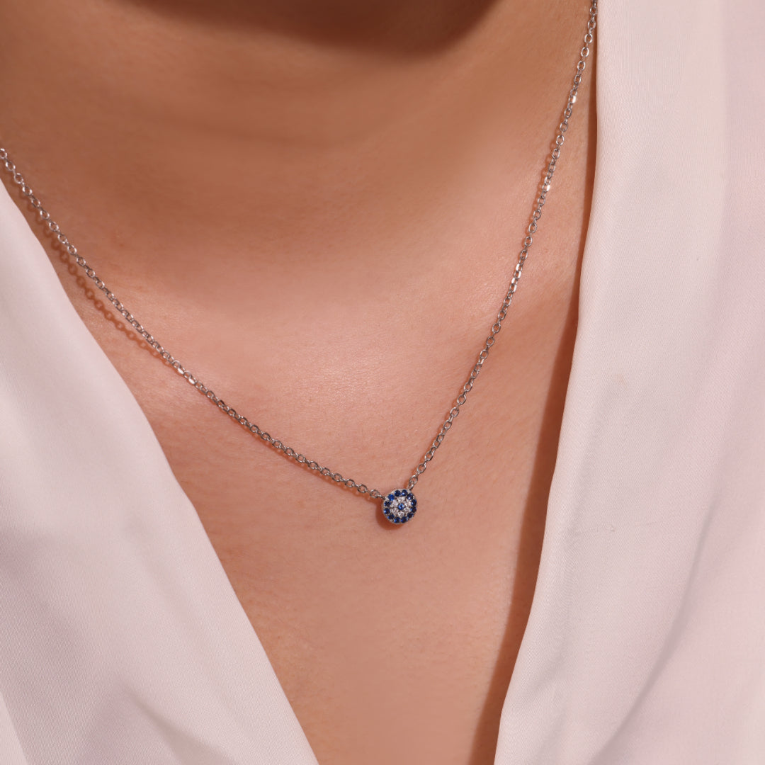 Collier fin en argent 925 avec un pendentif rond bleu serti de petites pierres scintillantes, symbolisant un œil bleu protecteur.
