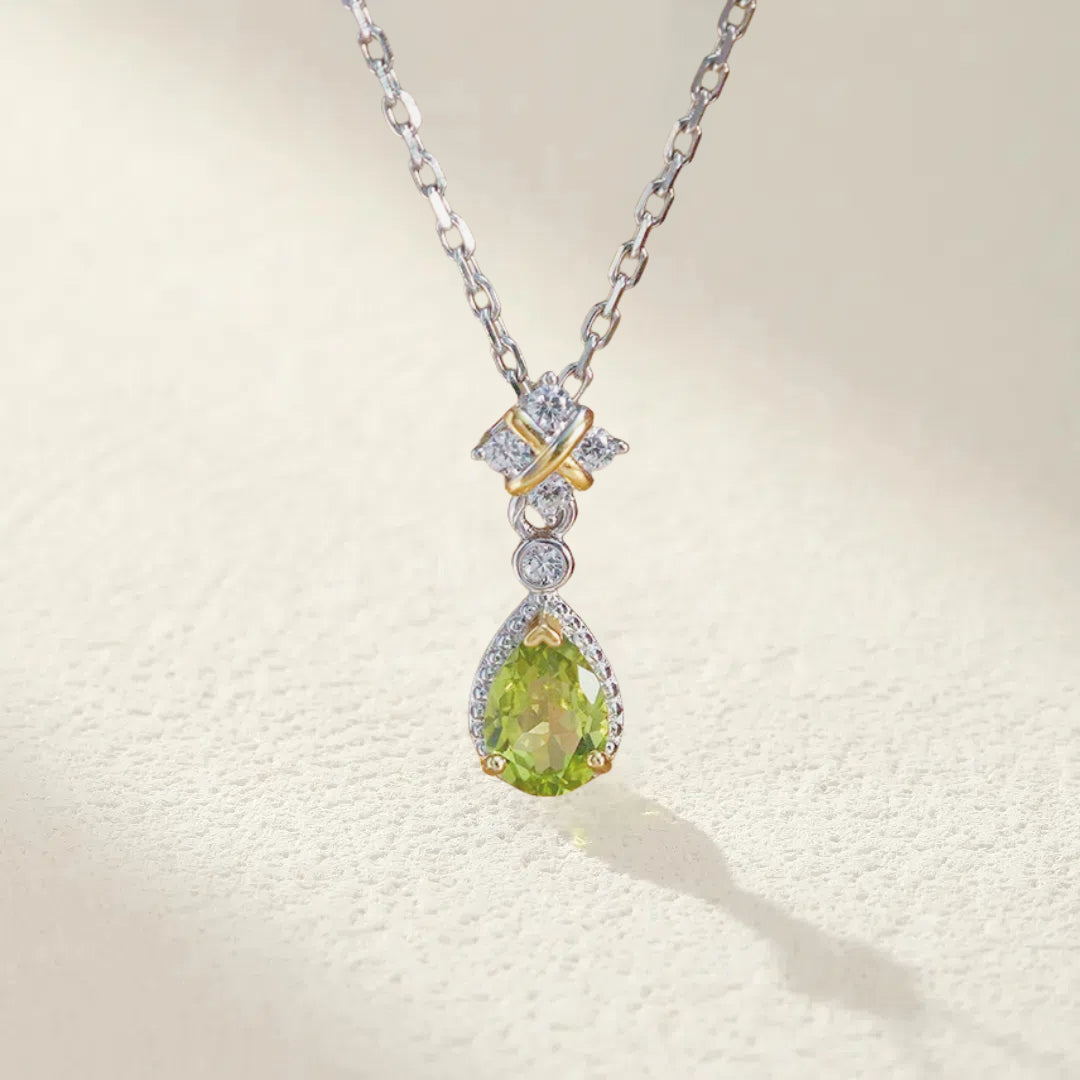 Collier en argent avec un pendentif en forme de goutte de péridot serti de petits diamants et orné d'une croisette dorée