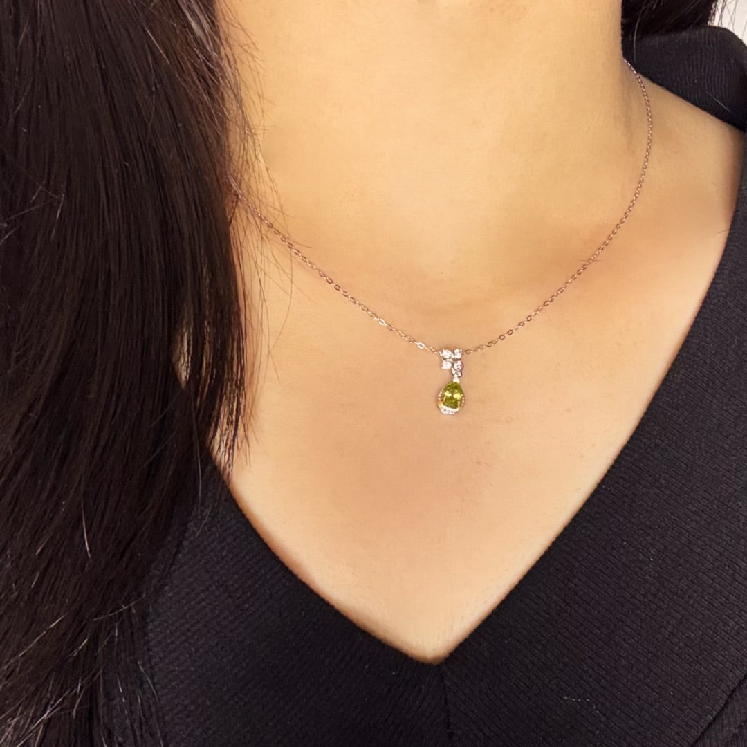 Collier en argent avec un pendentif en forme de goutte de péridot vert, orné de petites pierres d'imitation.