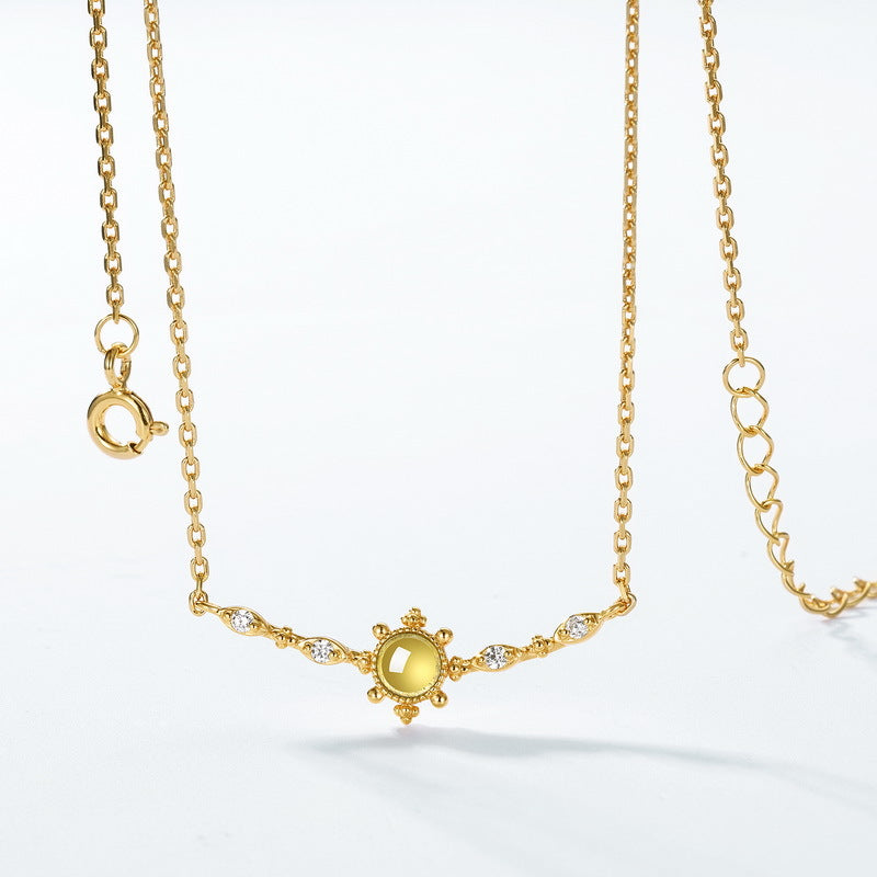 Collier en argent plaqué or avec un pendentif rond en péridot jaune entouré de diamants et de détails solaires, sur une chaîne délicate.