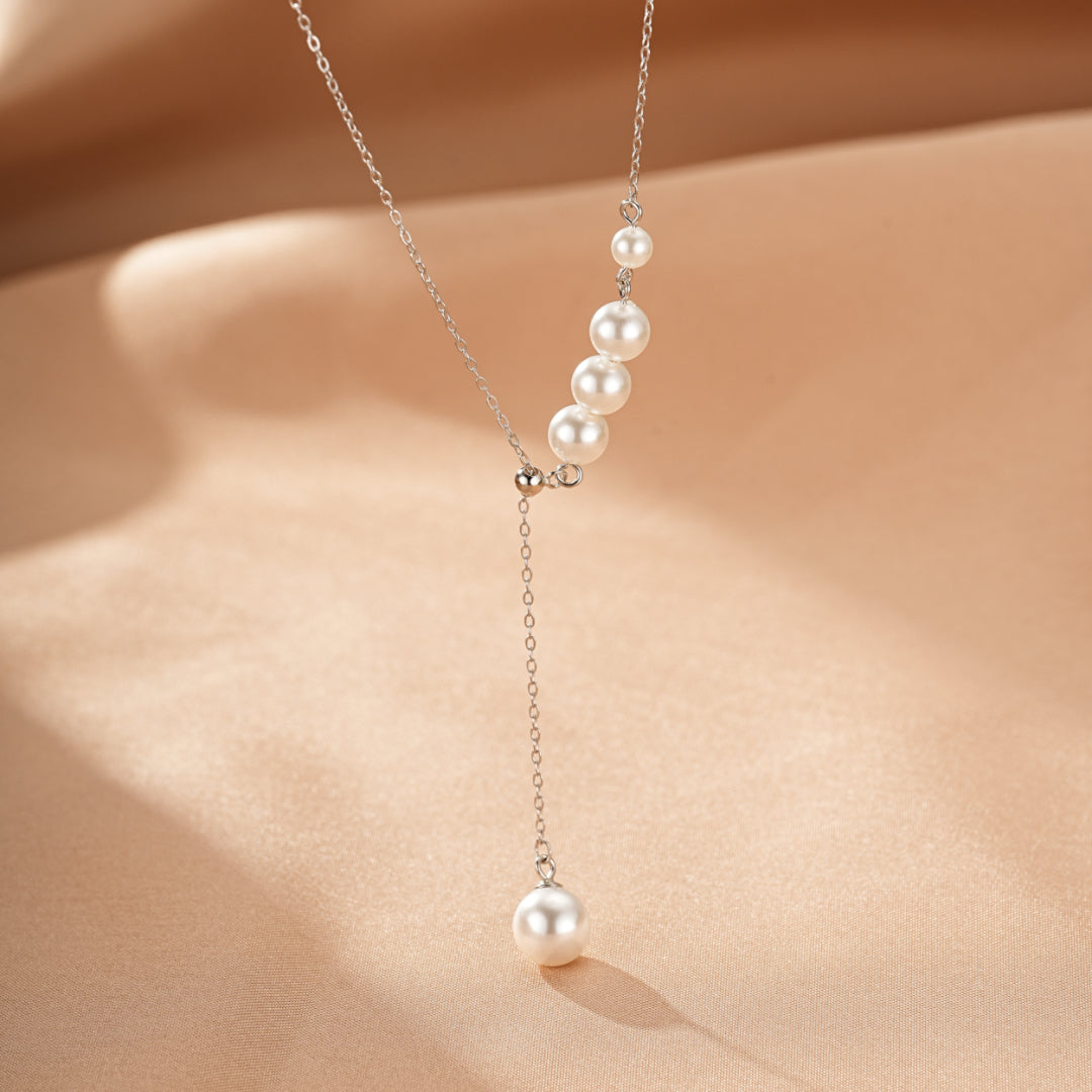 Collier en argent 925 avec une cascade de cinq perles blanches de tailles différentes, le pendentif tombant en Y.