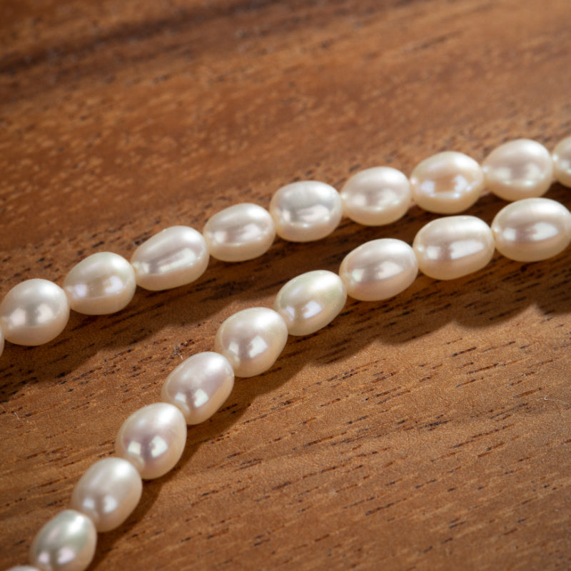 Collier de perles d'eau douce blanches sur fond de bois texturé