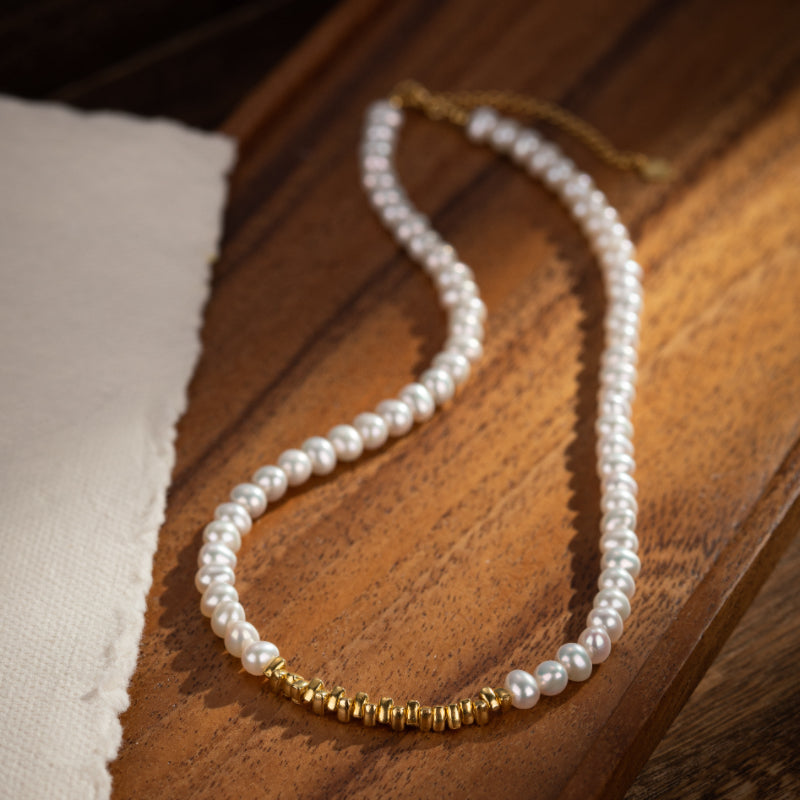 Collier de perles fines rehaussé de détails dorés sur fond de bois