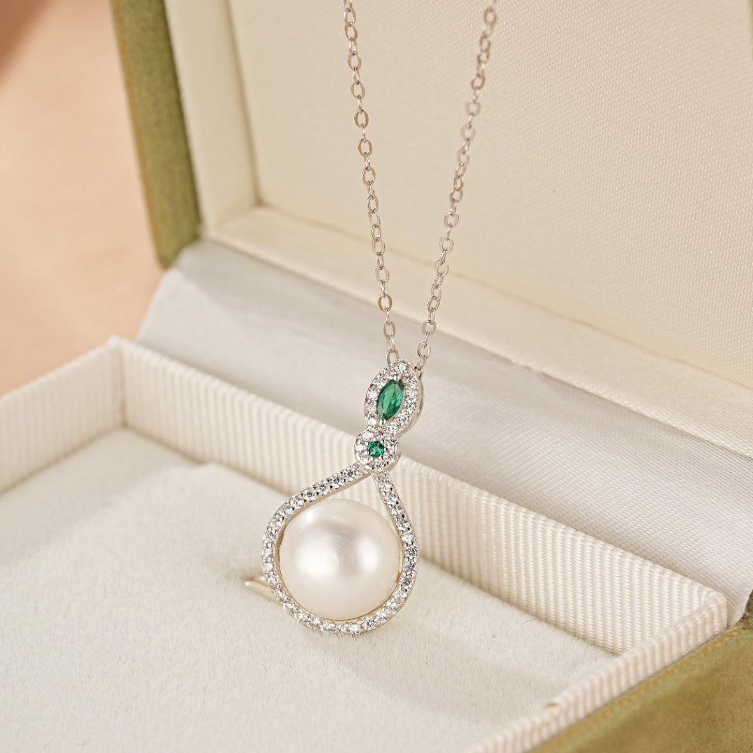 Collier en argent 925 avec une perle blanche, deux petites pierres vertes et de nombreux petits diamants incrustés dans un design en forme de goutte d'eau.