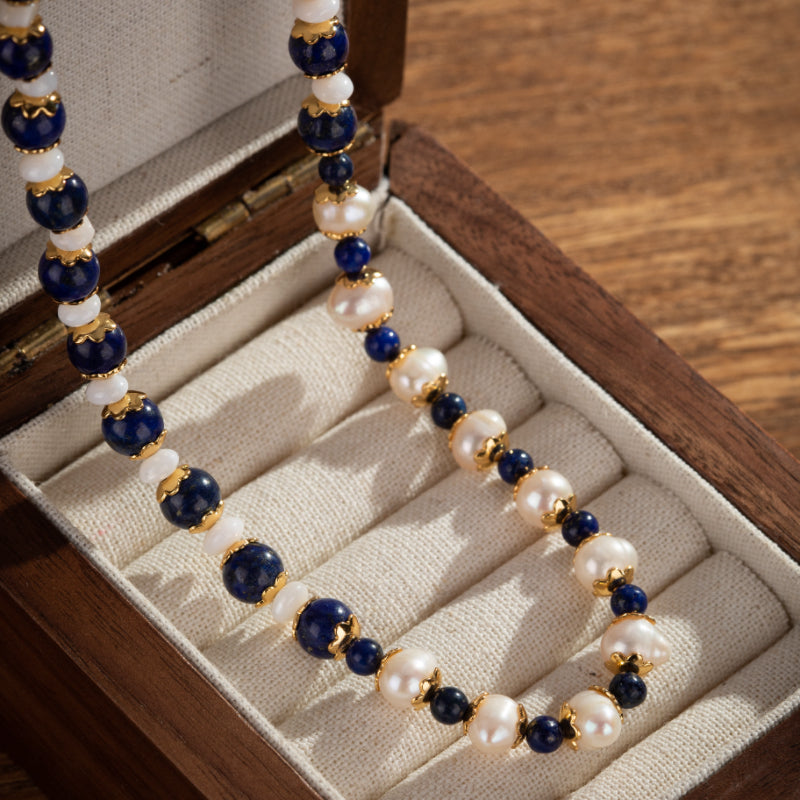 Collier en perles de lapis-lazuli et perles d'eau douce, monté sur plaqué or, présenté dans une boîte en bois.