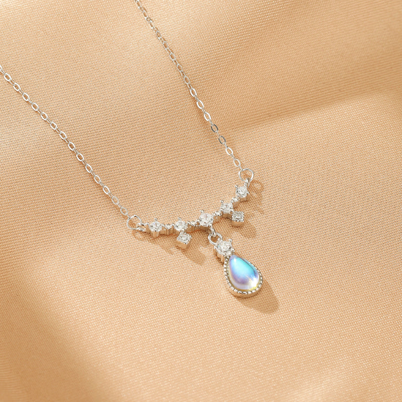 Collier Goutte Céleste en argent avec une pierre de lune bleu nacré et des cristaux brillants, monté sur une fine chaîne.