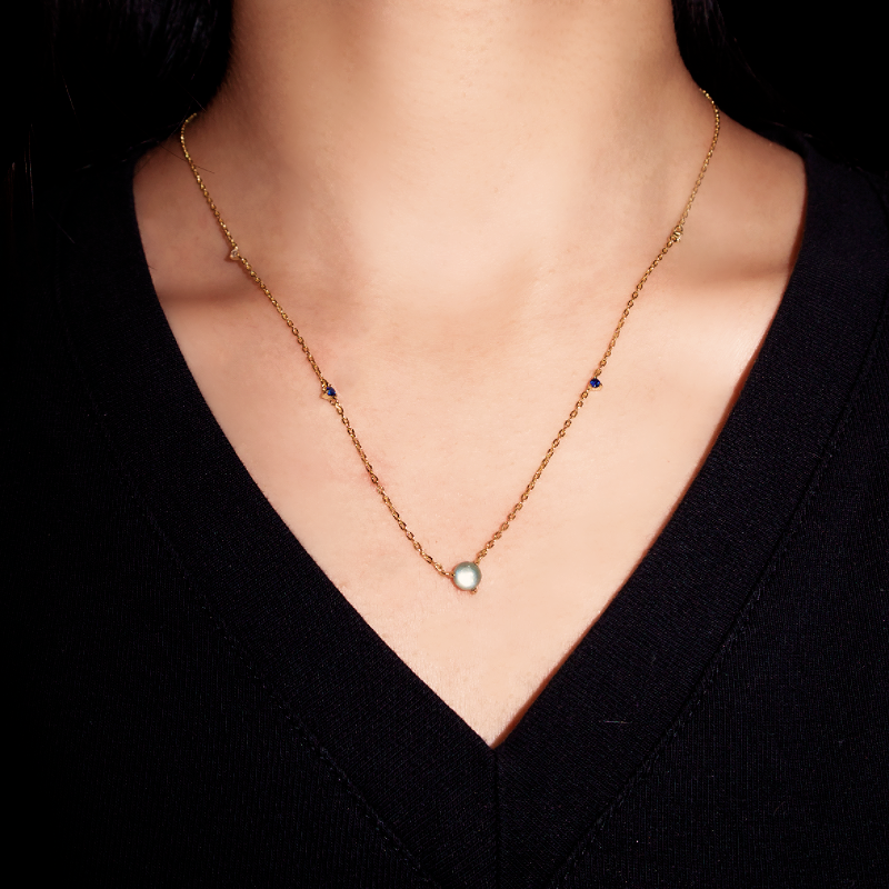 Collier fin en argent plaqué or 18 carats avec une pierre de lune centrale et de petites pierres bleues sur la chaîne.