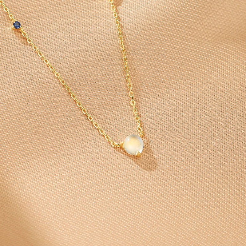 Collier fin en argent plaqué or 18K avec une pierre de lune nacrée et deux petites pierres bleues sur la chaîne.