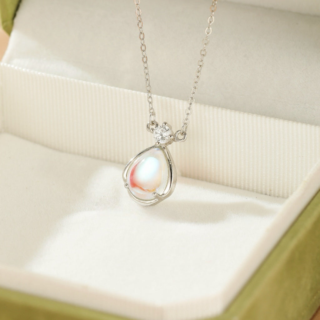 Collier en argent avec un pendentif en forme de larme orné d'une pierre de lune iridescente et d'un petit cristal.