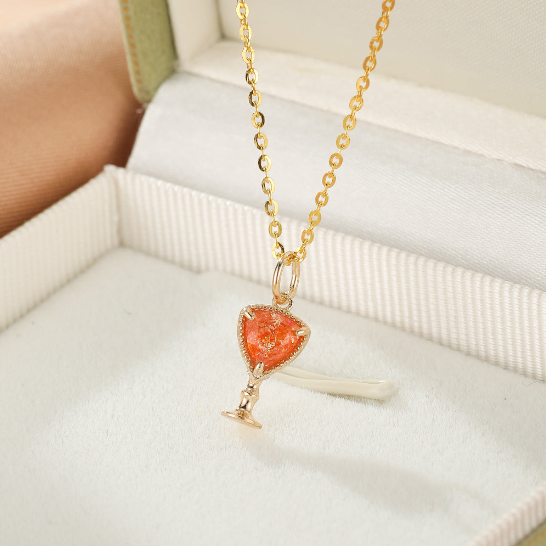 Collier en argent plaqué or avec un pendentif en forme de calice rempli d'une pierre de soleil orange scintillante.