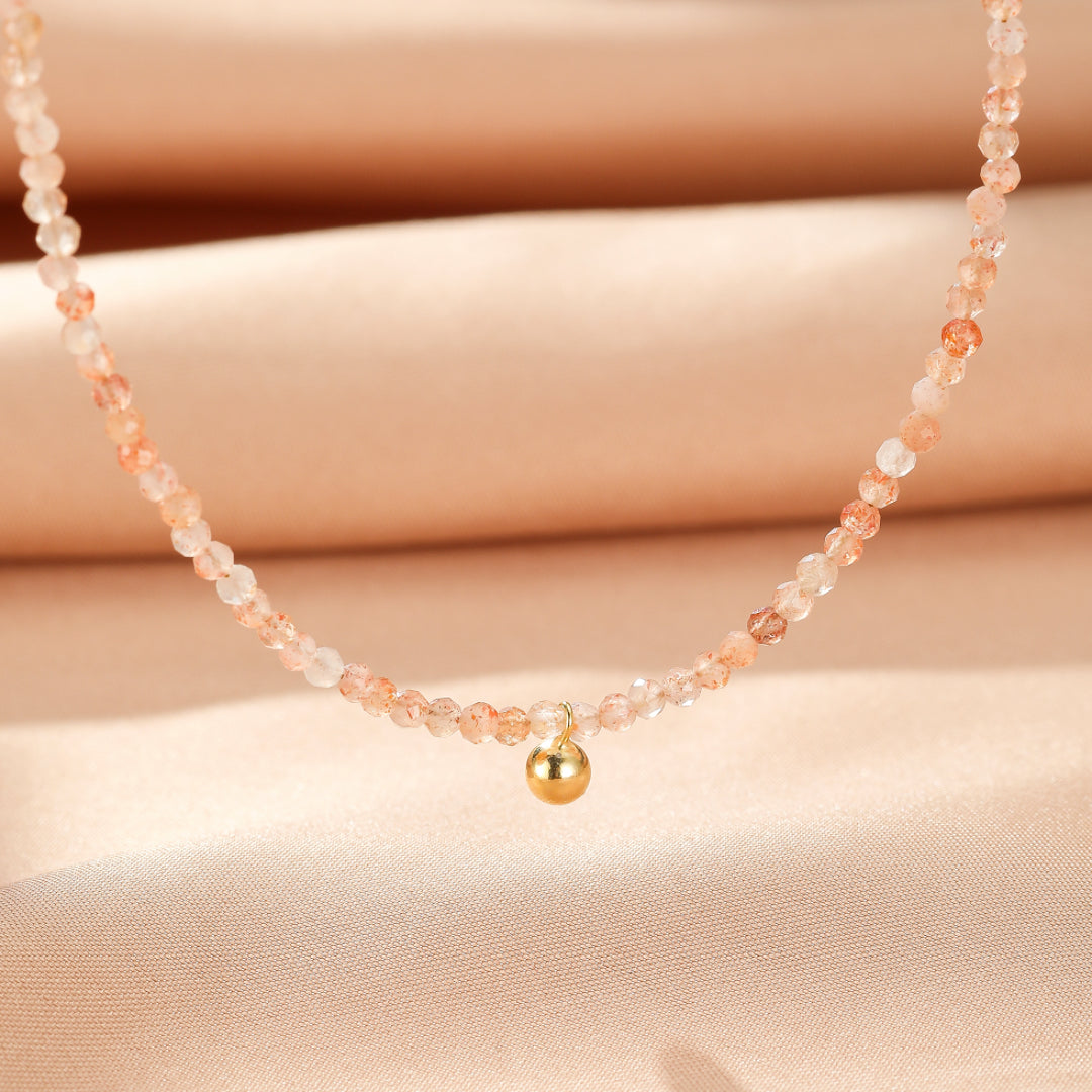 Collier délicat en argent plaqué or avec une chaîne de petites perles de pierre de soleil et une petite boule dorée au centre.