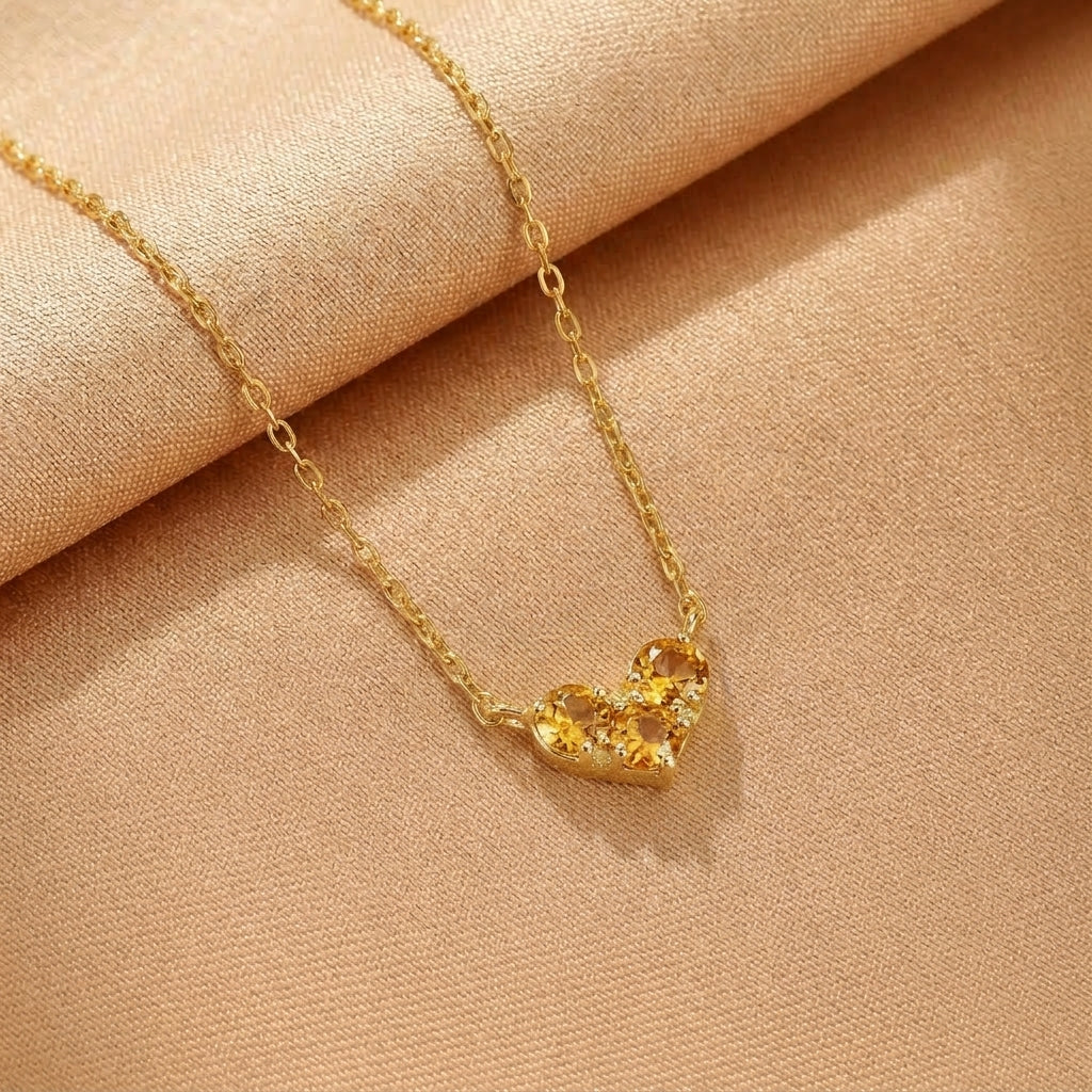 Collier en argent plaqué or avec un pendentif en forme de cœur serti de trois pierres jaunes scintillantes.