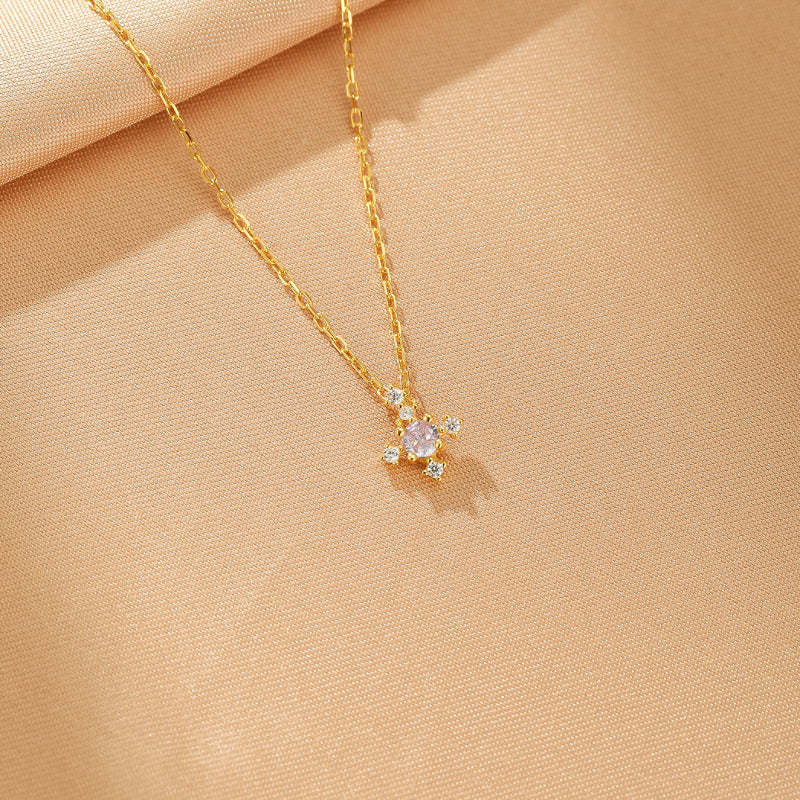Collier en argent plaqué or avec une pierre de naissance rose centrale et quatre petites pierres blanches scintillantes disposées en croix.