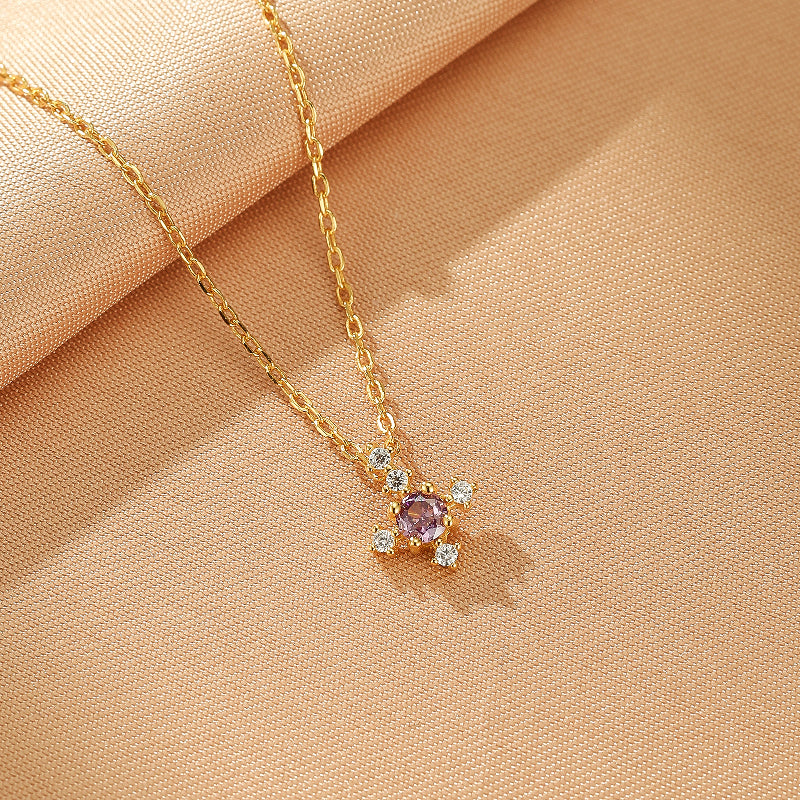 Collier en argent plaqué or avec un pendentif en forme de croix serti d'une pierre de naissance violette centrale et de petites pierres blanches scintillantes.
