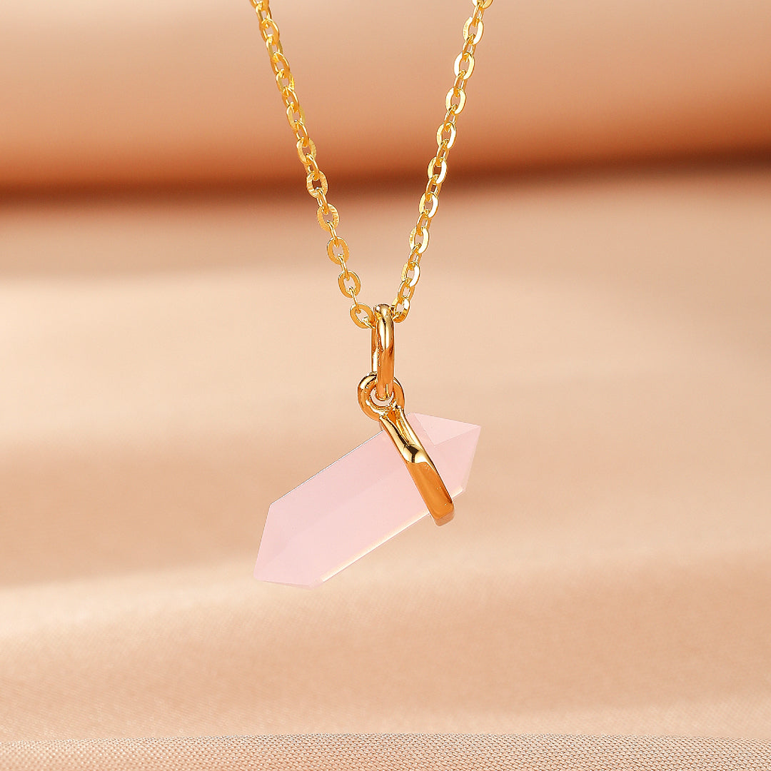 Collier en argent plaqué or 10K avec un pendentif en quartz rose brut à double pointe sur un fond rose pâle