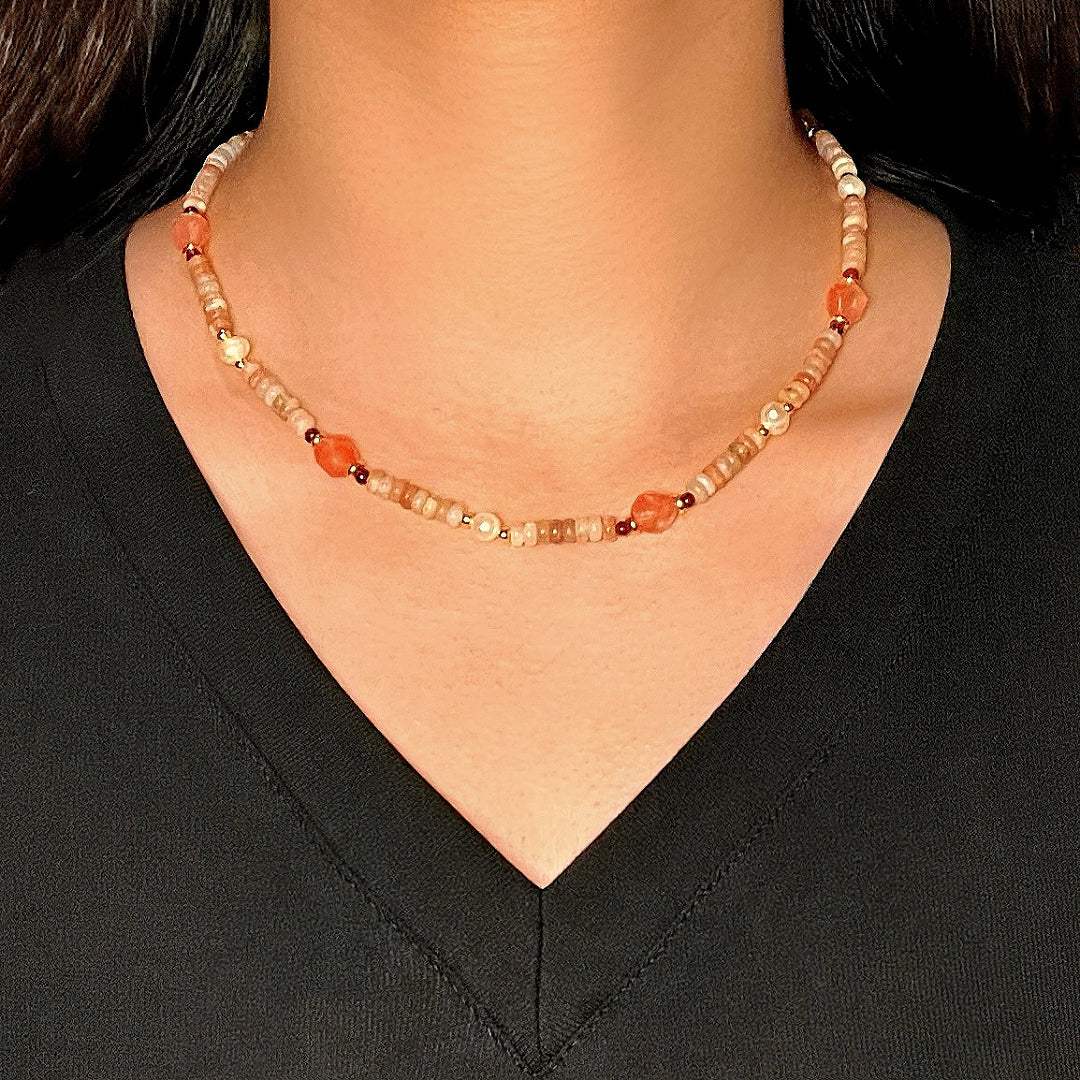 Collier artisanal en perles de rhodonite et pierres naturelles fines, avec des accents de quartz rose et de grenat, porté par une femme.