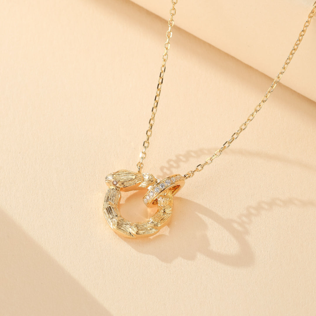 Collier serpent doré avec un cercle brillant incrusté de zircons cubiques, monté sur une chaîne délicate.