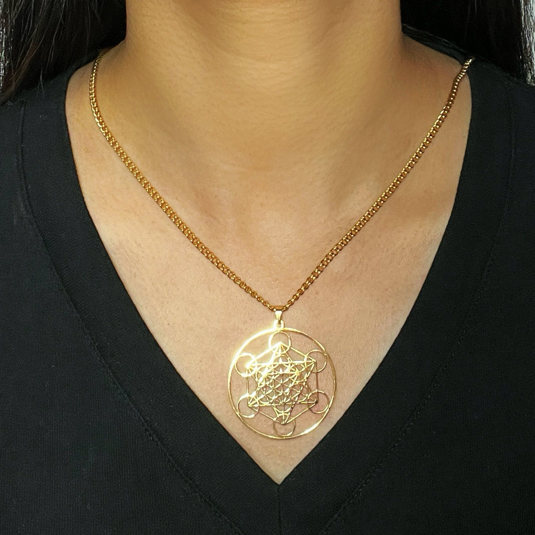 Collier en or avec un pendentif rond orné de la géométrie sacrée du Sri Yantra, porté par une femme.